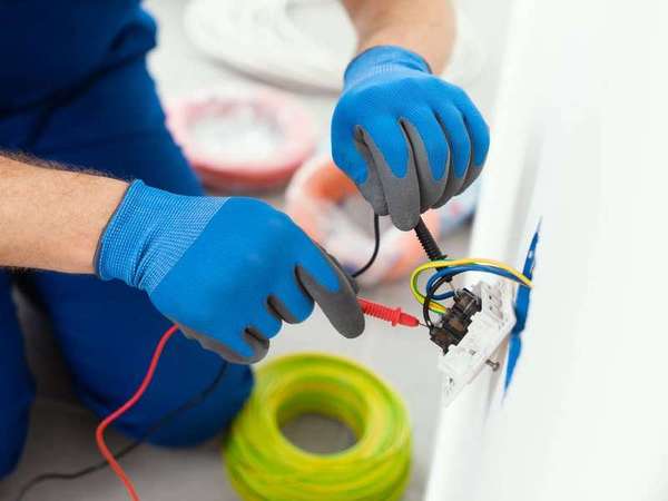 Electrician testing an outlet with a multimeter during an emergency call